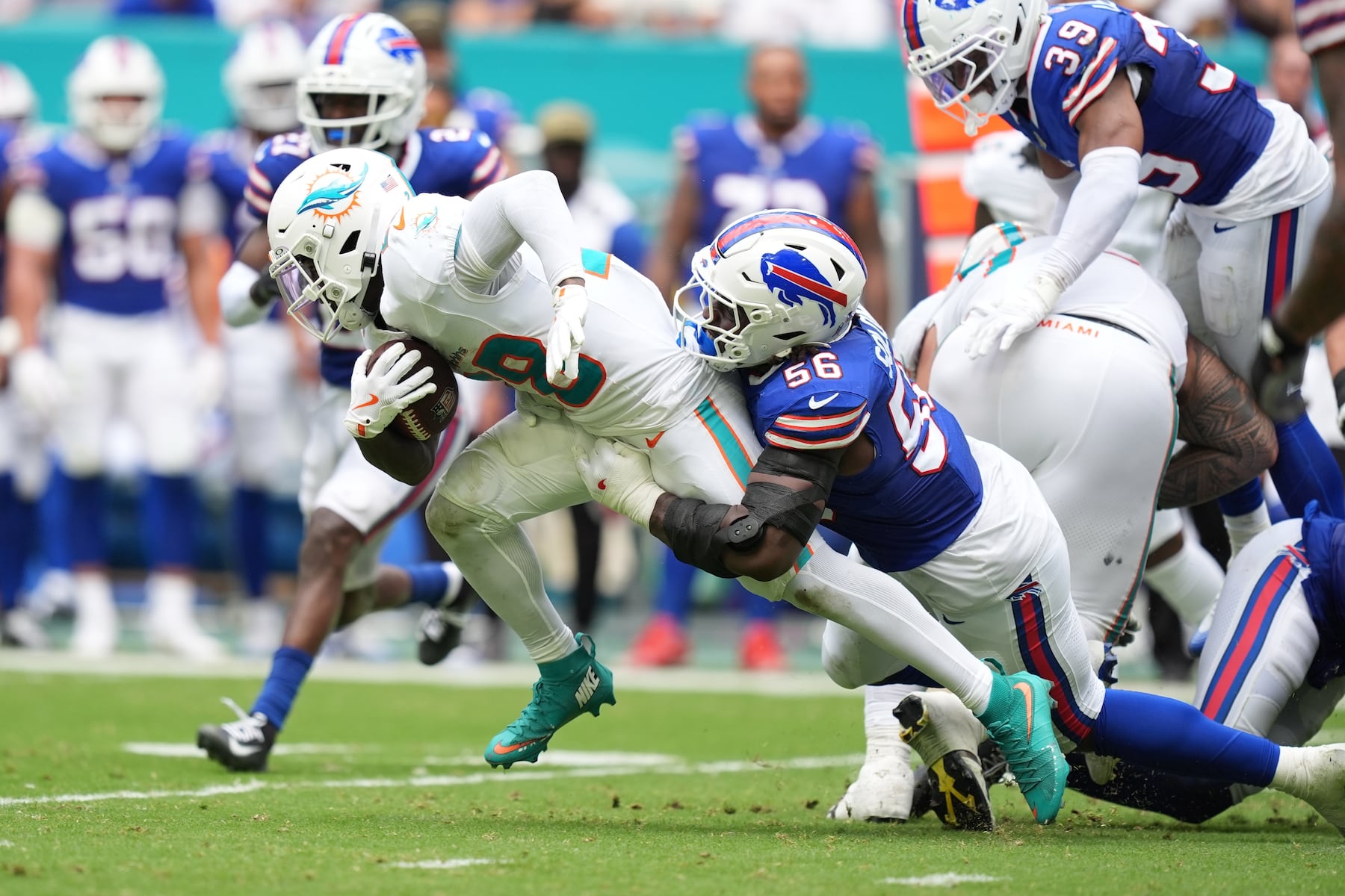 Miami Dolphins' De'Von Achane (28) is tackled by Buffalo Bills' Javon Solomon (56) during the first half of an NFL football game, Sunday, Nov. 9, 2025, in Miami Gardens, Fla. (AP Photo/Rebecca Blackwell)