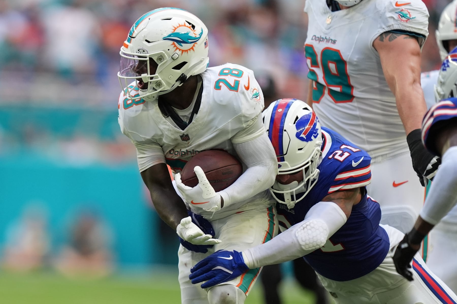 Miami Dolphins' De'Von Achane (28) is tackled by Buffalo Bills' Jordan Poyer (21) during the first half of an NFL football game, Sunday, Nov. 9, 2025, in Miami Gardens, Fla. (AP Photo/Rebecca Blackwell)