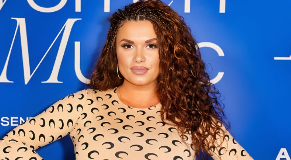 Joy Taylor posing in front of blue background